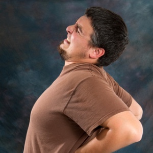Picture of person holding their back with a link to the Symptoms we deal with page.